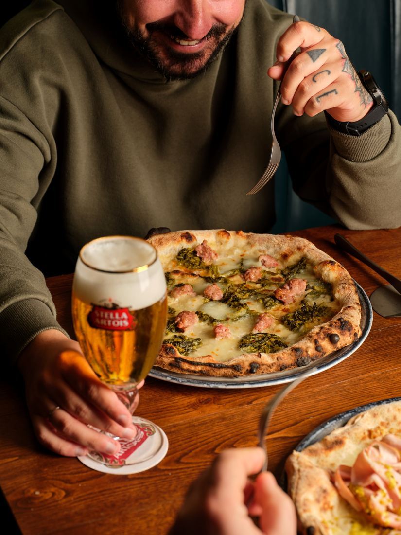 Un cliente con pizza in teglia e birra