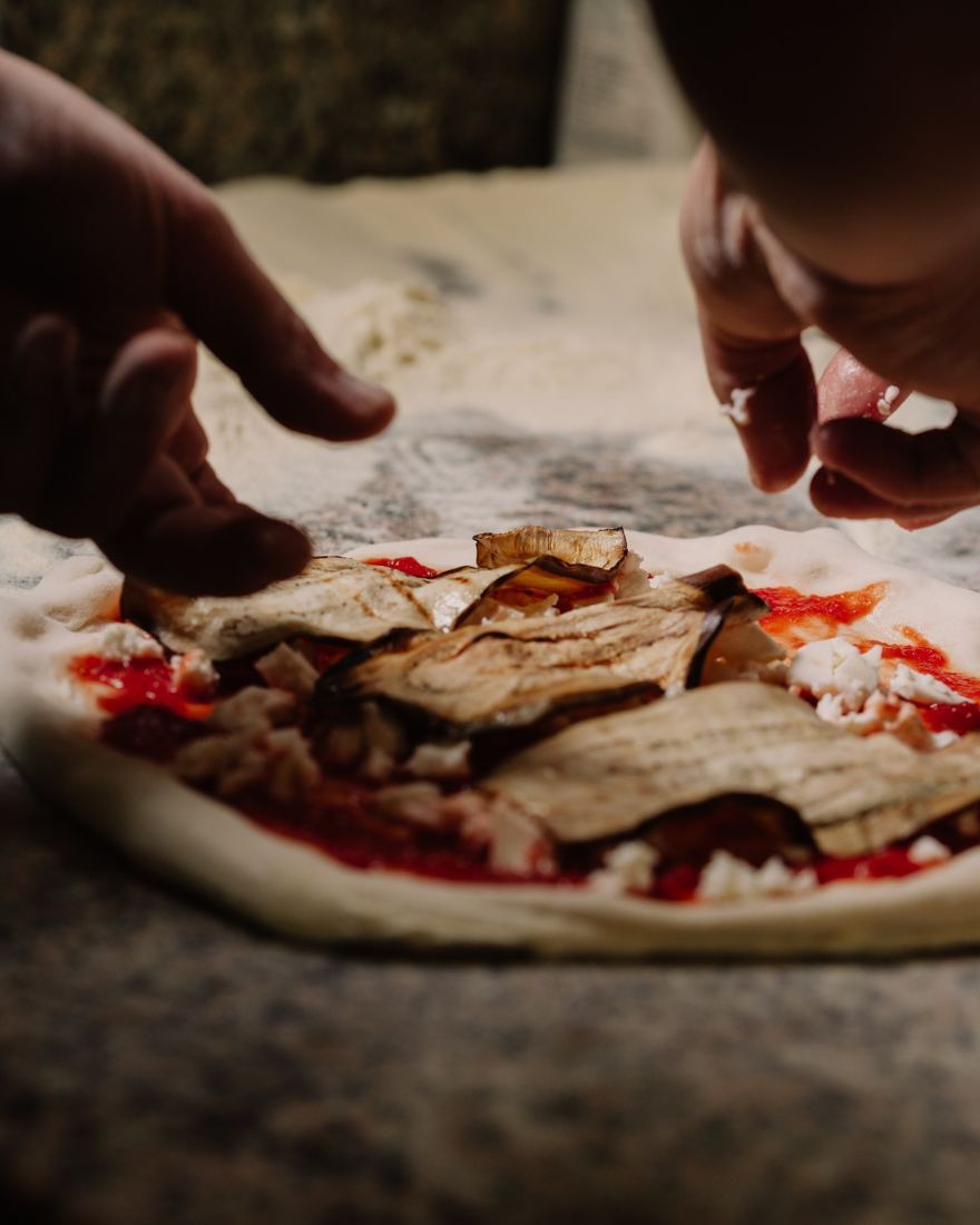 La pizza girata viene condita a mano