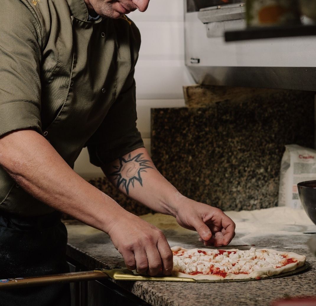Il pizzaiolo stende l’impasto lievitato a mano